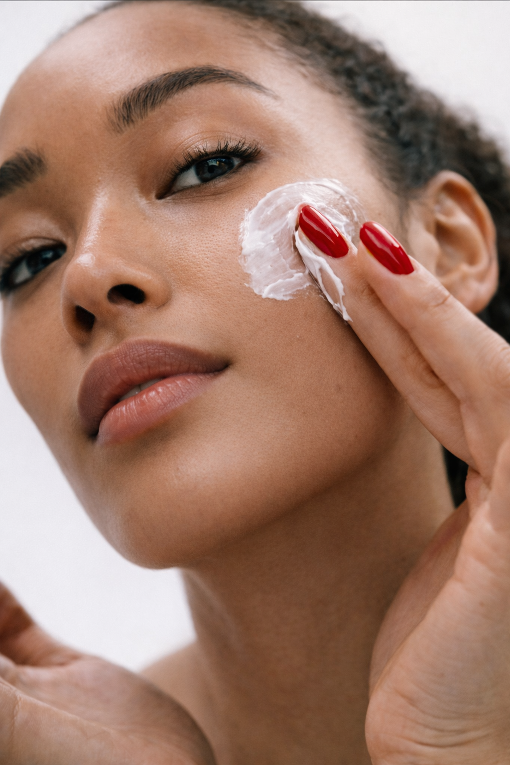 Woman applying cream to her face with a white background