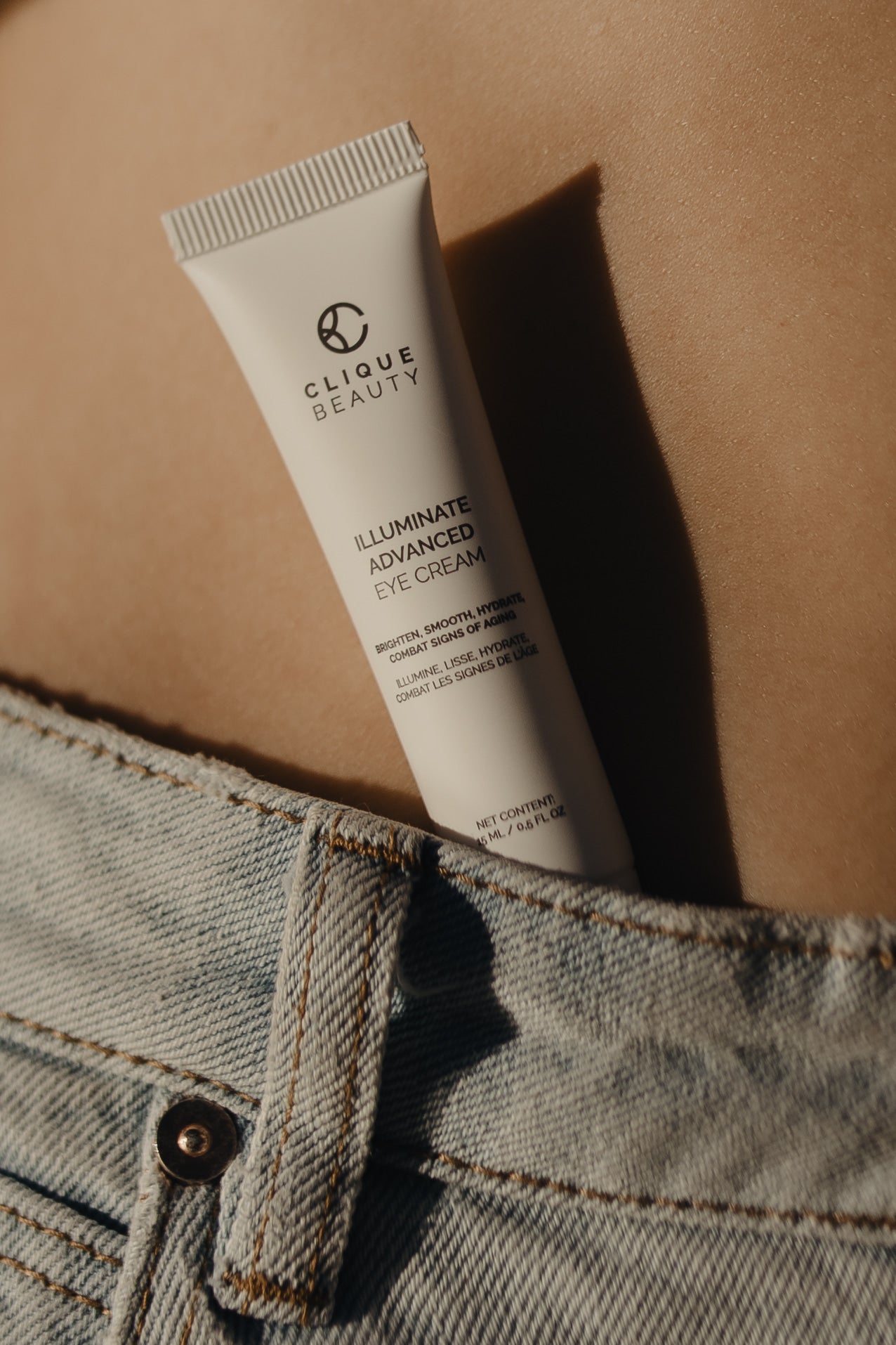 Clique Beauty Illuminate Advanced Eye Cream tube on a beige background