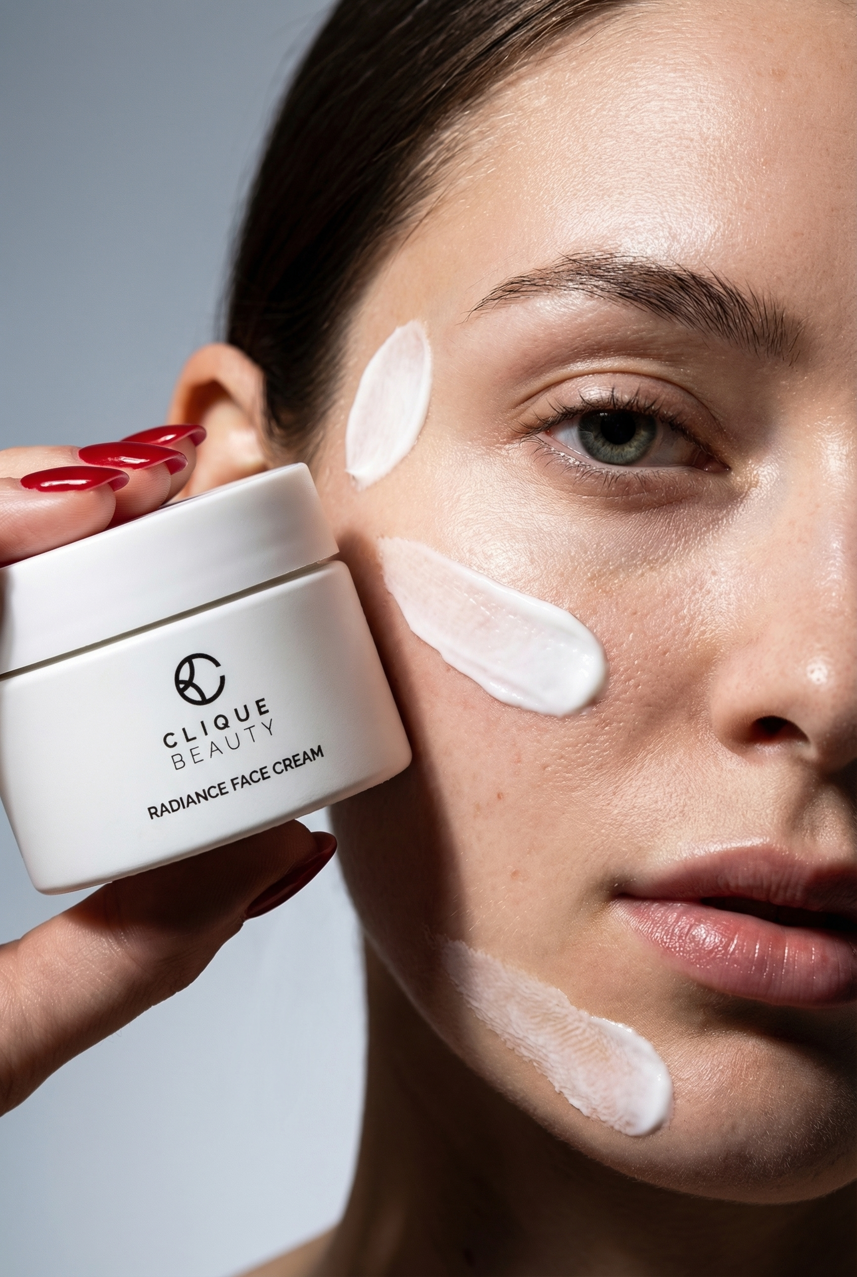 Woman applying Clique Beauty radiance face cream to her face with a gray background